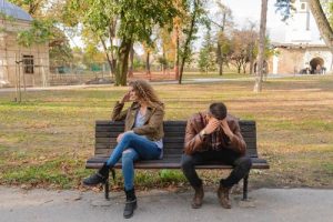 Unhappy couple sitting on a bench struggling with the question of why stay in an unhappy marriage.