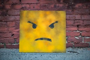 Yellow square metal face that appears to be feeling contempt.