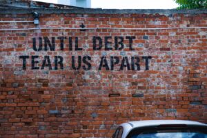 Brick wall with the words "Until Debt Tear Us Apart" written on it.