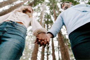 Couple holding hands in a forest as they discuss attending a private couples marriage retreat.