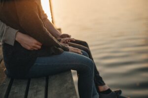 Couple sitting on dock cuddling after a weekend marriage retreat.