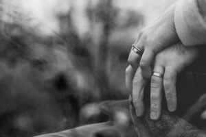 Couple holding left hands and displaying their wedding bands.
