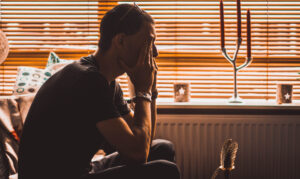 Man holding his face in his hands as he wonders how to find help surviving infidelity.