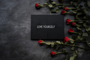 Appeal for self-love: Love yourself sign surrounded by red roses.