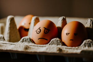 Eggs in a carton where one has a worried expression and the other's is upset.