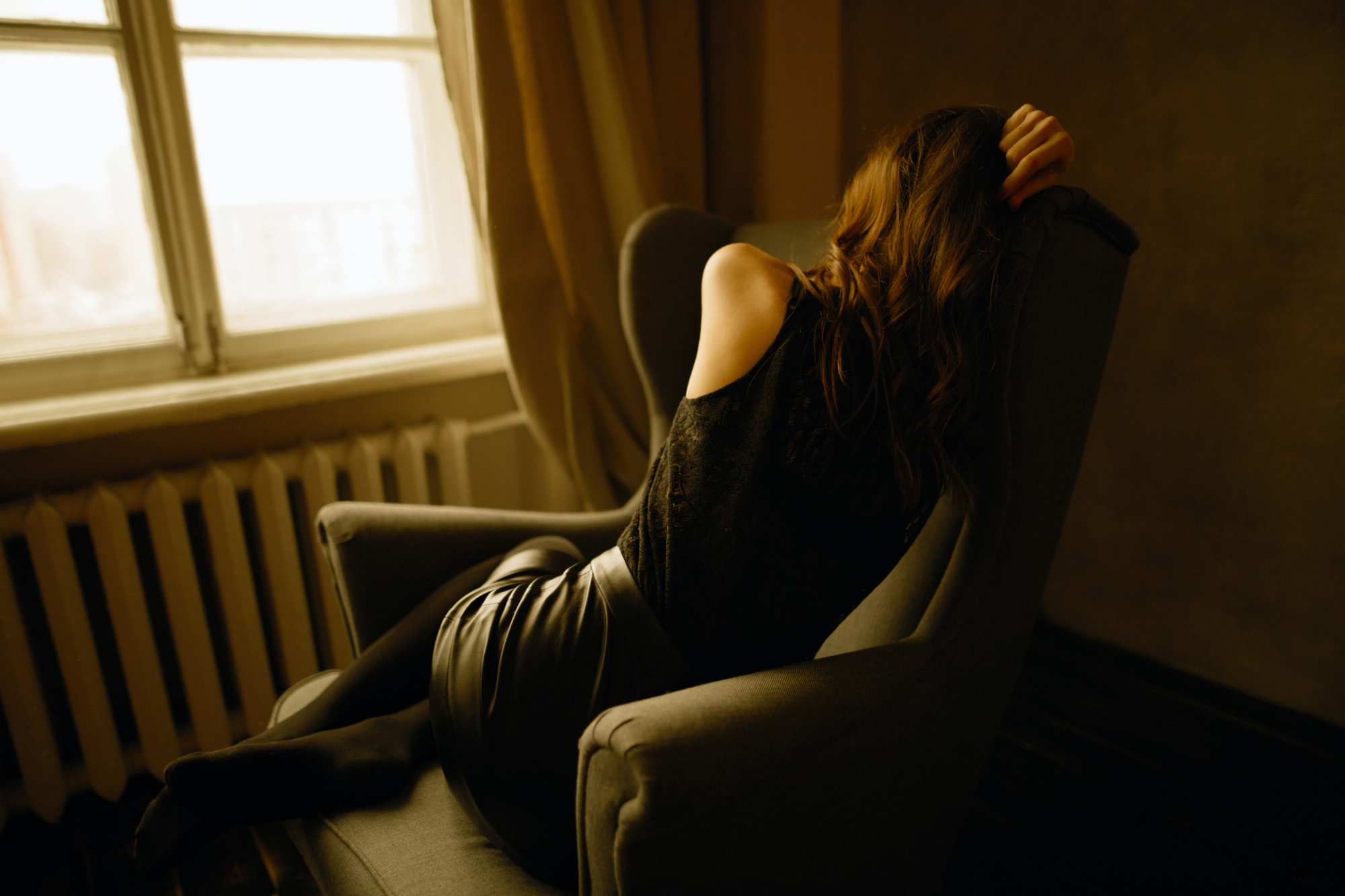 Depressed woman huddled in a chair, contemplating her unhappy marriage.
