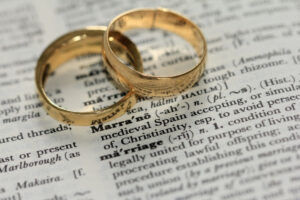 2 wedding bands place on a dictionary above the word "marriage".