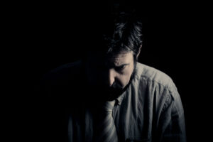 Man sitting in the dark and looking dejected because he's living in a sexless marriage.