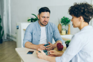 Couple sitting across the table from each other as they figure out how to handle the silent treatment in their marriage.