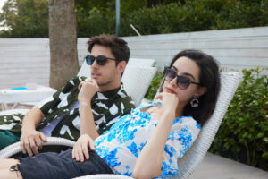 A man and a woman, bored in marriage, lounge apart on beach chairs.