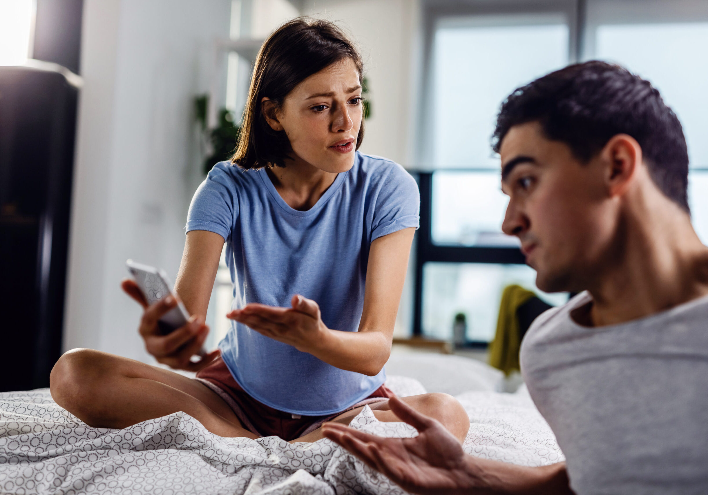 How are you explaining this text message? Disappointed woman arguing with her boyfriend about text message on mobile phone.